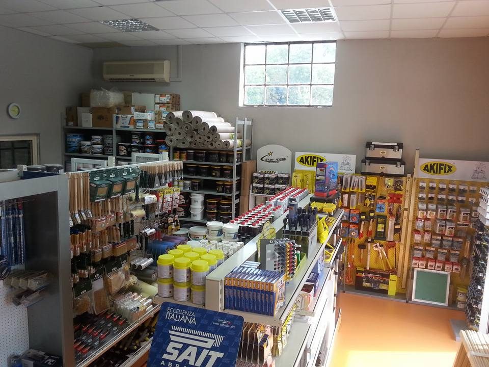 Interno Tecnoedil con pennelli, rotoli bianchi, barattoli, espositori gialli Akifix di attrezzi e cartello SAIT